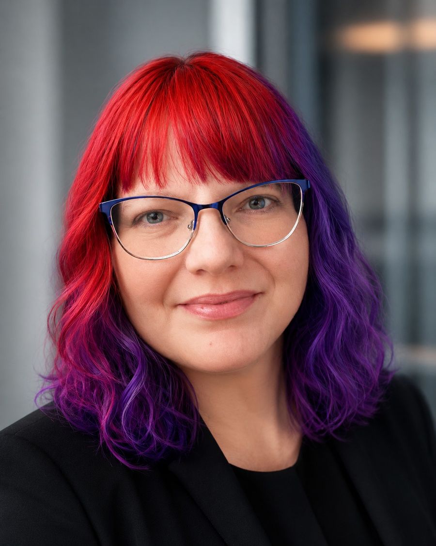 Anny Levine, founder of myMadrich, smiling, with bright red and purple hair and glasses