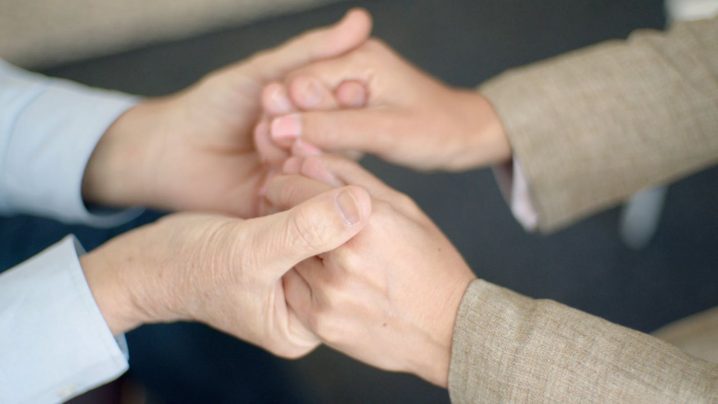 Two people holding hands in support